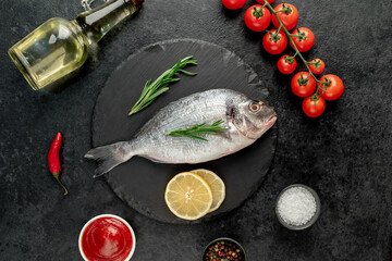 raw dorado fish with lemon and rosemary on stone background