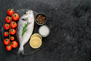 raw dorado fish with lemon and rosemary on stone background with copy space for your text