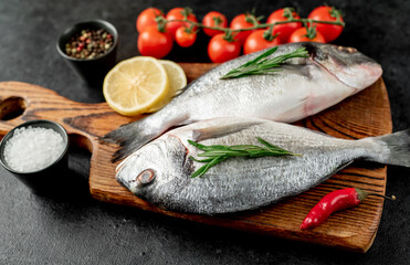 raw dorado fish with lemon and rosemary on stone background