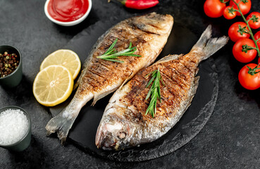 grilled dorado fish with lemon and rosemary on stone background