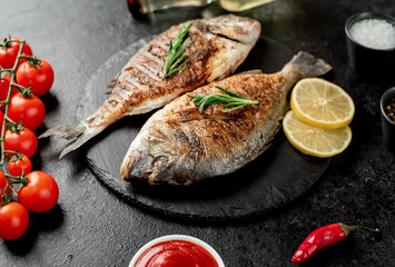 grilled dorado fish with lemon and rosemary on stone background