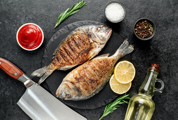 grilled dorado fish with lemon and rosemary on stone background