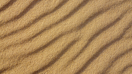 Fototapeta na wymiar Brown wavy sand texture close up, beautiful natural natural background