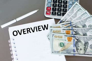 OVERVIEW text on a notebook next to a calculator and money on the table