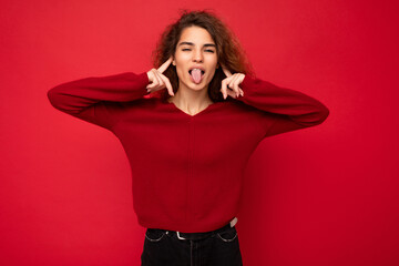 Photo of young positive happy attractive brunette wavy-haired woman with sincere emotions wearing casual red sweater isolated on red background with empty space and having fun