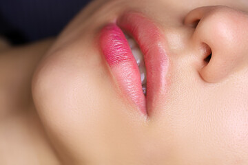 close-up of the lips of a young model who has a tattoo on her lips made up to the middle