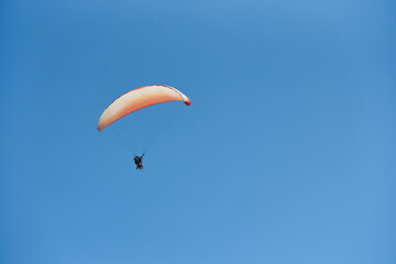Paragliding with two people against blue sky