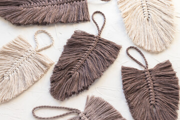 Macrame feathers leaves made of cotton rope yarn in brown and natural color on white background. Handmade, creative hobby. Top view, flat lay.