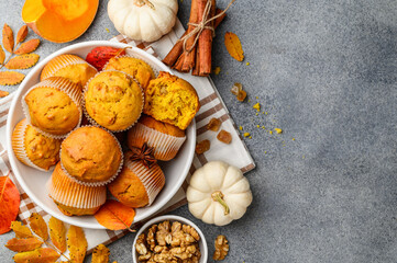 Pumpkin muffins or cupcakes with walnuts on a white plate. Autumn bakery. Healthy vegetarian dessert. Copy space