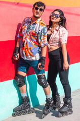 Two young fashionable skaters on a colorful street 
