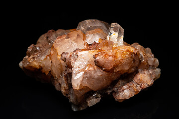 Mineral stone Quartz cluster isolated, selective focus on black table. Natural pure brown shiny rock found in the river. Macro close up of glassy brown orange raw Quartz crystal. Home decoration.