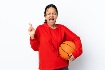 Young woman playing basketball over isolated white background with fingers crossing