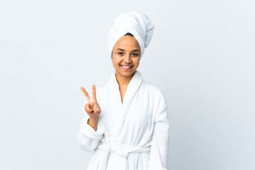 Young woman in bathrobe over isolated white background smiling and showing victory sign