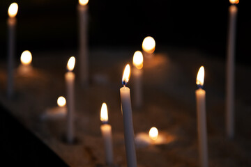 Candle light. Candles light in dark background. Candle flames in catholic church. Bokeh effect.