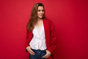 Portrait of positive cheerful fashionable woman in formalwear looking at camera isolated on red background with copy space