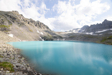 Obraz premium Amazing hiking day in one of the most beautiful area in Switzerland called Pizol in the canton of Saint Gallen. A wonderful view at the alpine lake called Wildsee with a tent by the lake. Epic view.