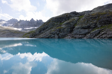 Obraz premium Amazing hiking day in one of the most beautiful area in Switzerland called Pizol in the canton of Saint Gallen. A wonderful view at the alpine lake called Wildsee with a tent by the lake. Epic view.