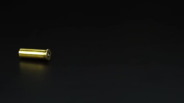 Bullet casings from a .38mm pistol falling closeup on black floor. Slow motion.