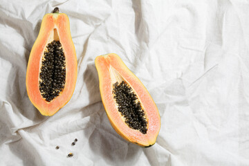 creative food concept with half papaya on crumpled gray linen.