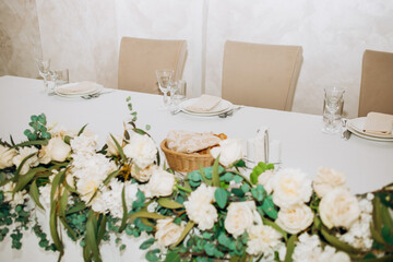 Wedding. Banquet. Chairs and a round table for guests, served with cutlery, flowers and utensils and covered with a tablecloth. Beige colors