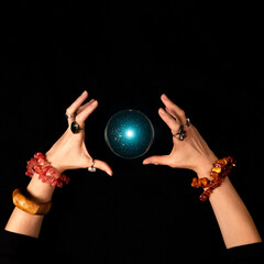 Fortune teller or witch hands and a glowing magic ball isolated on dark background. Halloween, magic and tricks concept