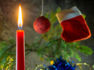 Christmas red candle burns against the background of fir branches.