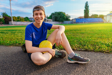 teen boy posing with ball at a stadium, a soccer field with green grass - sports and health concept