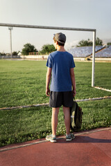 concept of sports and health - teen boy posing at a stadium, a soccer field with green grass.