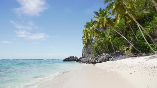 A volcanic beach with white sand and large black stones. Tropical vacation on a paradise island. Sea beach and sky on a sunny summer day.