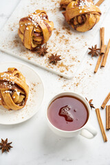 Fresh vegan cinnamon buns on marble board and white marble table