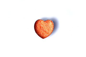 Heart shaped small orange balls on a white background. Round bath salt. Isolate.