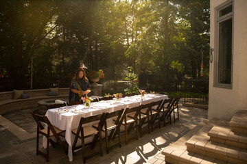 Woman setting table for an outdoor dinner party 