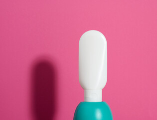 empty white plastic tube for cosmetics on a pink background with shadow. Containers for cream, shampoos, liquid substances. Branding, template