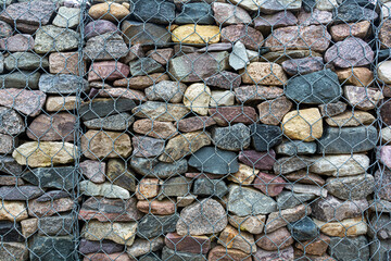 Gabion close-up. Abstract background. A three-dimensional product made of wire and stones to strengthen the shore or landscape.