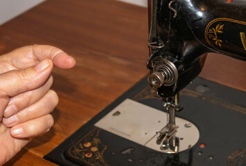 Old women’s hands using an antique sewing machine