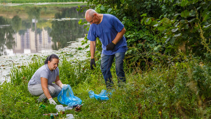 Naklejka na ściany i meble A woman and a man volunteers clean up garbage from a landfill in the park.
