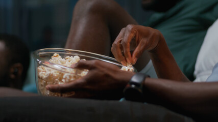 Black man eating popcorn and watching match with friends