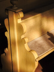 Vertical shot of an old wooden pew in the church under sunbeams