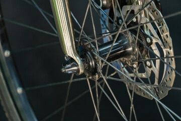 A photo of the front bicycle wheel taken in a professional studio with studio light and a black background. High-quality bicycle workshop, mountain bike repair, tire and brake close-up.