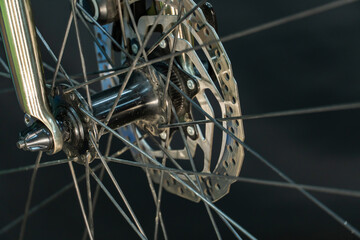 A photo of the front bicycle wheel taken in a professional studio with studio light and a black background. High-quality bicycle workshop, mountain bike repair, tire and brake close-up.
