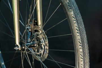 A photo of the front bicycle wheel taken in a professional studio with studio light and a black background. High-quality bicycle workshop, mountain bike repair, tire and brake close-up.