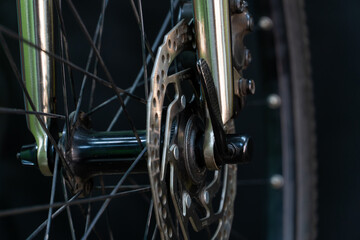 A photo of the front bicycle wheel taken in a professional studio with studio light and a black background. High-quality bicycle workshop, mountain bike repair, tire and brake close-up.