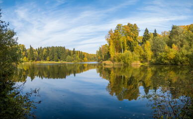 A lake in a forest under a blue sky with clouds