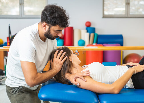 Physiotherapist doing manual stretching and resistance techniques to reduce neck pain in a young Caucasian female patient.