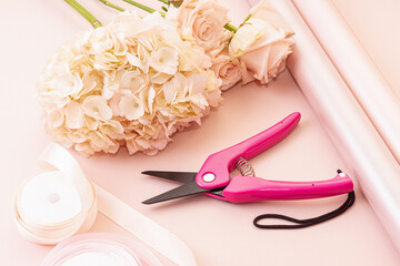 Florist makes a spring bouquet. Hydrangea, roses, ribbons, wrapping paper and floral scissors. Gift for woman