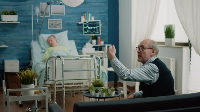 Worried man asking medical team to help sick old wife in nursing home. Doctor and nurse rushing to give assistance to ill retired patient hyperventilating, laying on hospital bed