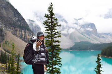 Fototapeta na wymiar Young girl with backpack calling her companion to see and admire the beauty of turquoise lake and mountains