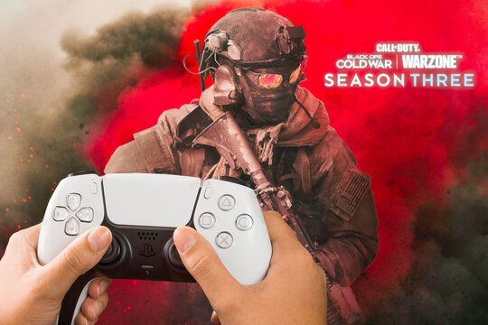 Female hand holding a Playstation 5 Dual Sense Controller with Call of Duty Season Three game blurred in the background. Rio de Janeiro, RJ, Brazil. October 2021.