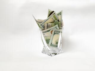 A pile of dollars in a whiskey glass on a white isolated background. Retirement savings in dollars. Pension amount