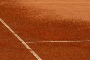 Watering or moistening of clay tennis court. Surface of sports field, marking lines are visible. Design element. Fragment of covering, wet and dry, selective focus